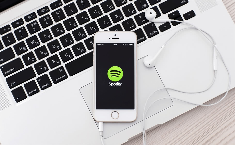 Music Streaming: An iPhone showing Spotify with earbuds sprawled upon a Macbook
