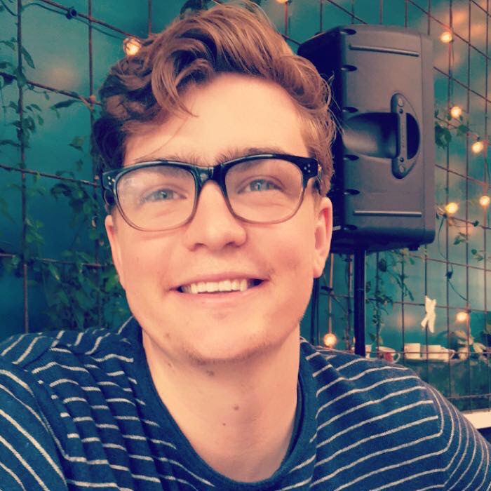 Finn-McLennan-Elliot-Second-Hand wearing glasses striped blue t shirt