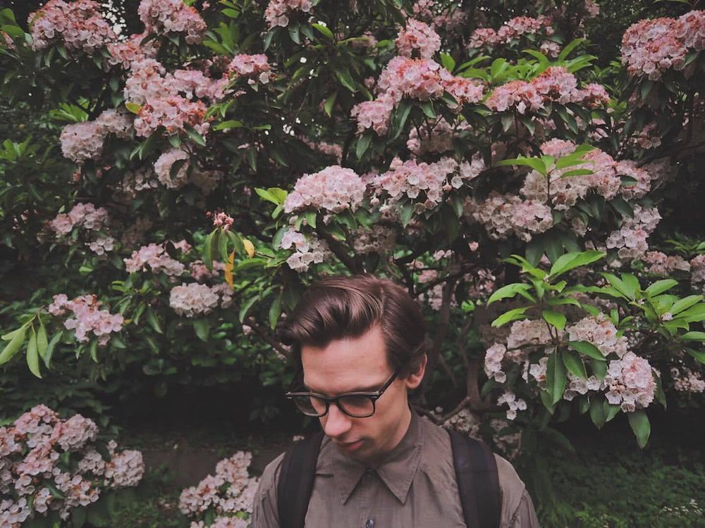 Marty Hicks in front of tree with flowersn wearing backpack
